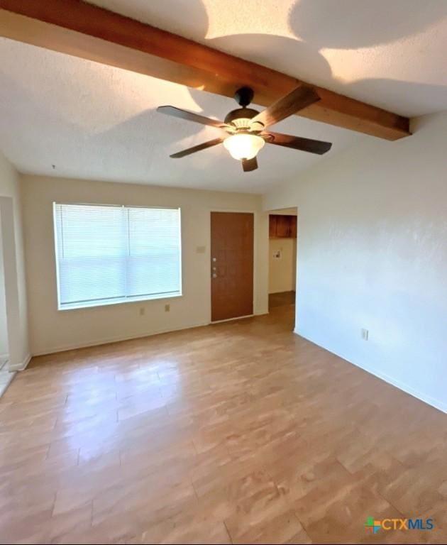 empty room with ceiling fan and lofted ceiling with beams