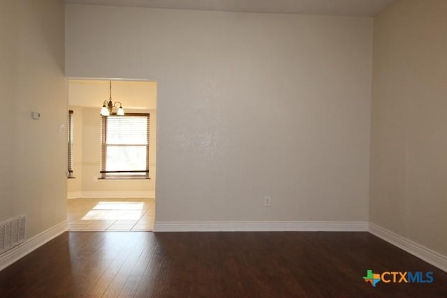 spare room with hardwood / wood-style floors and an inviting chandelier