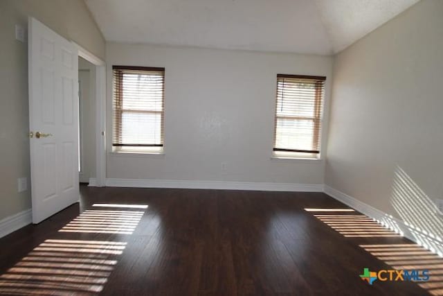 unfurnished room featuring dark hardwood / wood-style floors and vaulted ceiling