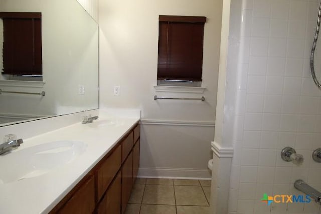 bathroom featuring tile patterned flooring, a tile shower, vanity, and toilet