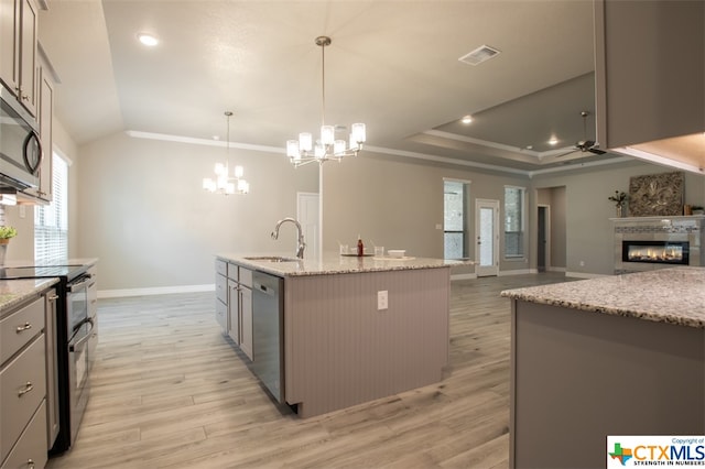 kitchen featuring stainless steel appliances, sink, a kitchen island with sink, pendant lighting, and light wood-type flooring