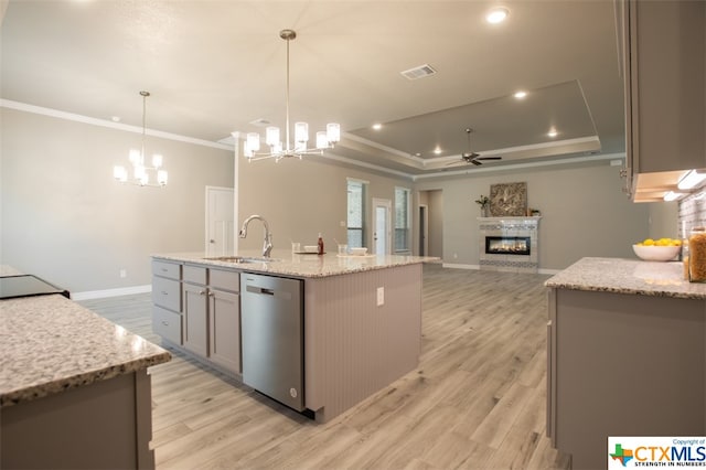 kitchen with a center island with sink, dishwasher, hanging light fixtures, sink, and light hardwood / wood-style flooring