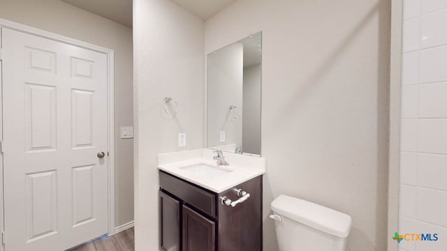 bathroom with hardwood / wood-style floors, vanity, and toilet