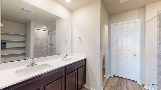 bathroom with hardwood / wood-style floors, vanity, toilet, and a shower with door