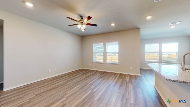 unfurnished room featuring a wealth of natural light, hardwood / wood-style floors, and ceiling fan