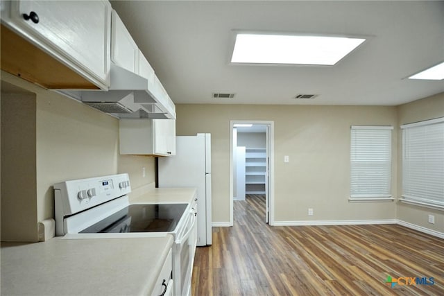 kitchen with white electric range oven, white cabinets, and visible vents