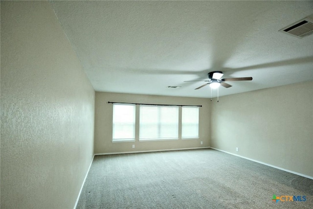 carpeted spare room with a textured ceiling, baseboards, a ceiling fan, and visible vents