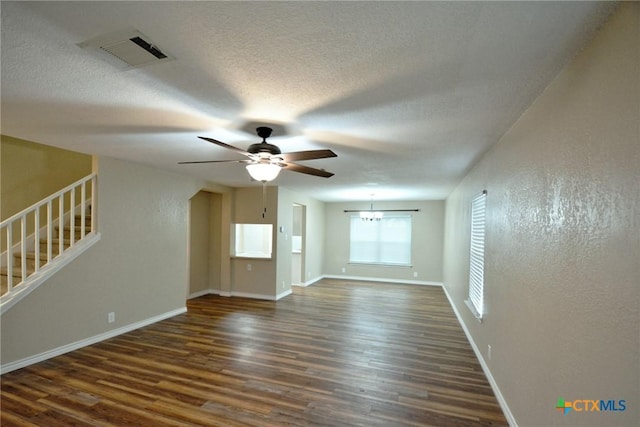 unfurnished living room with baseboards, dark wood-style flooring, ceiling fan, visible vents, and stairs