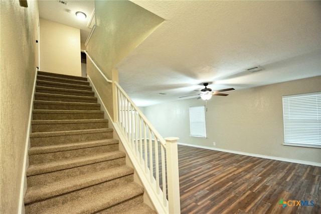 stairway featuring a ceiling fan, baseboards, visible vents, and wood finished floors