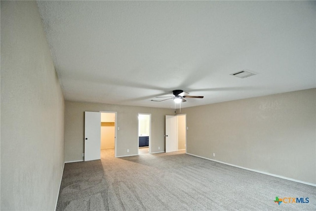 carpeted empty room featuring ceiling fan, baseboards, and visible vents