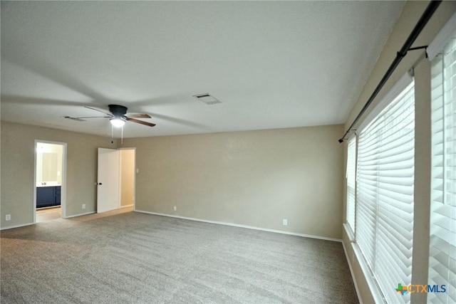 empty room featuring carpet flooring, baseboards, a ceiling fan, and visible vents