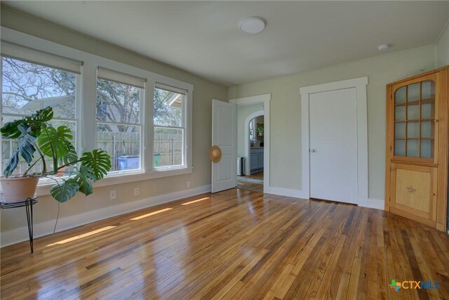 923 N Heideke St, Seguin, TX 78155 - unfurnished bedroom with wood-type flooring, arched walkways, and baseboards