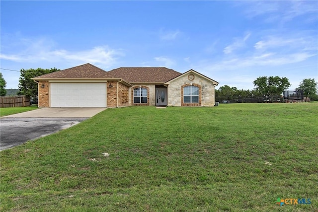 ranch-style house featuring fence, a front yard, brick siding, concrete driveway, and an attached garage