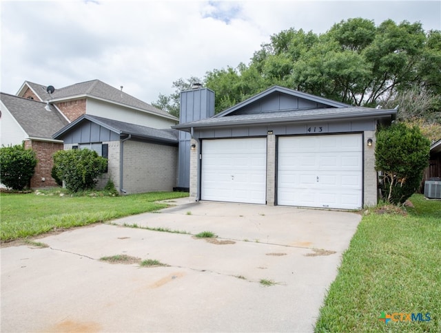 view of front of property featuring central AC unit, a garage, and a front yard