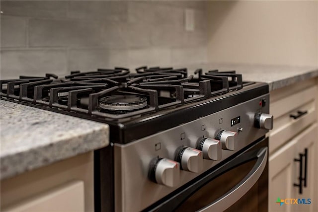 interior details with white cabinets, light stone counters, and stainless steel gas range