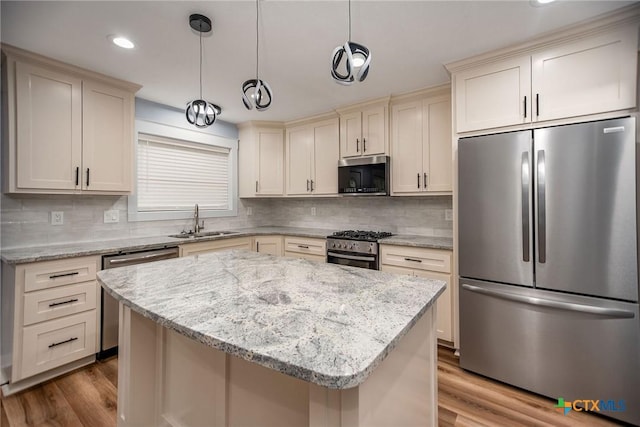 kitchen with decorative light fixtures, a kitchen island, sink, and appliances with stainless steel finishes