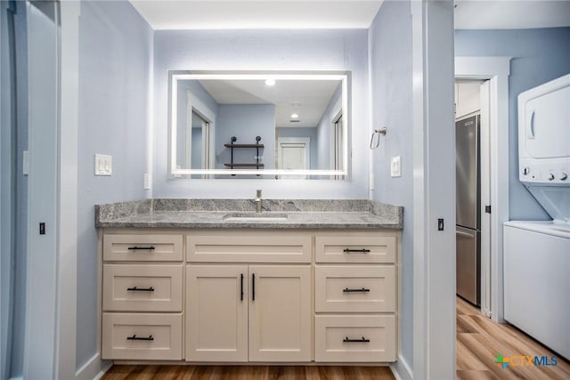 bathroom with vanity, stacked washing maching and dryer, and wood-type flooring