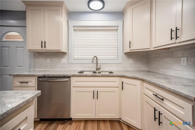 kitchen with decorative backsplash, light stone counters, sink, light hardwood / wood-style flooring, and dishwasher