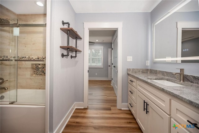 bathroom featuring hardwood / wood-style flooring, vanity, and shower / bath combination with glass door