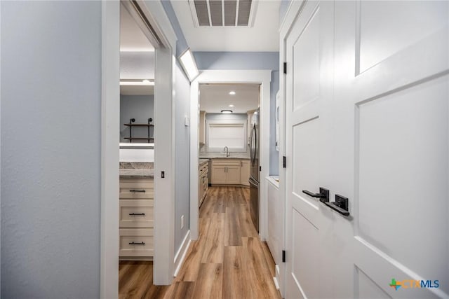 corridor featuring light hardwood / wood-style flooring and sink