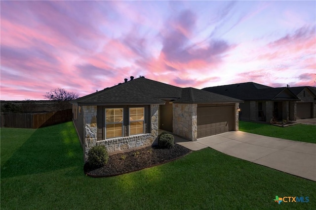 view of front of home featuring concrete driveway, stone siding, roof with shingles, an attached garage, and a yard