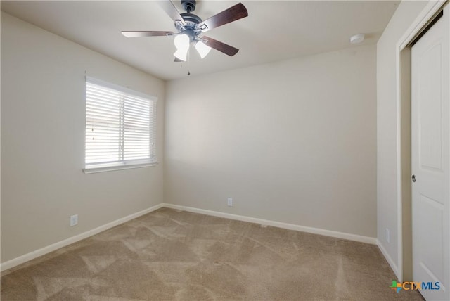 spare room featuring light carpet, ceiling fan, and baseboards