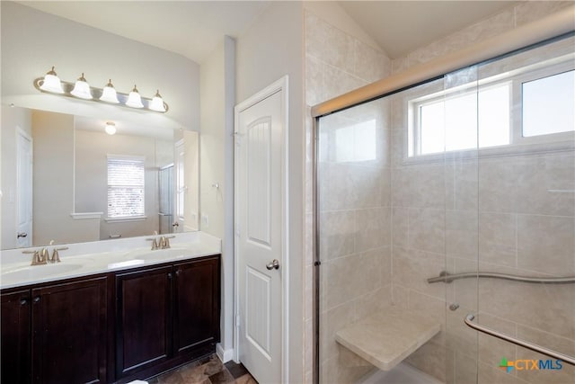 full bath with a stall shower, a sink, and a wealth of natural light