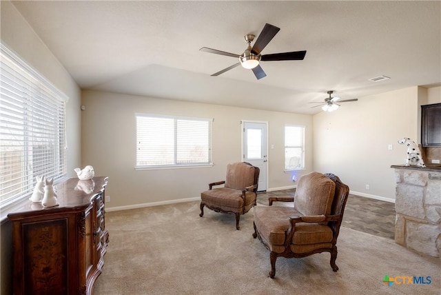 living area featuring visible vents, baseboards, ceiling fan, and light colored carpet