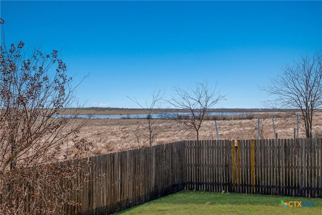 view of yard featuring a water view and a fenced backyard