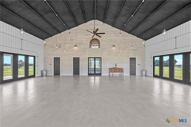 unfurnished living room featuring high vaulted ceiling, ceiling fan, a wealth of natural light, and concrete flooring