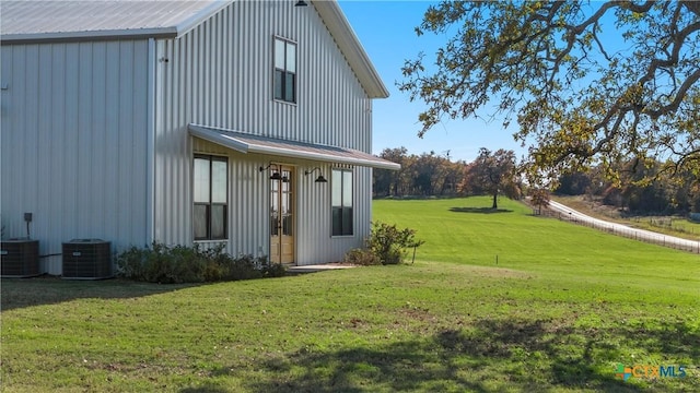 rear view of property featuring cooling unit and a lawn