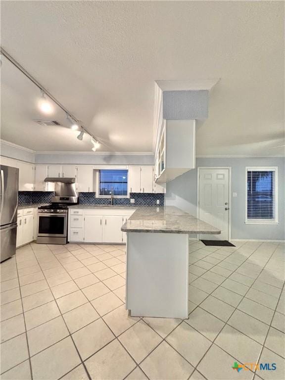 kitchen featuring appliances with stainless steel finishes, white cabinets, light tile patterned floors, kitchen peninsula, and light stone countertops