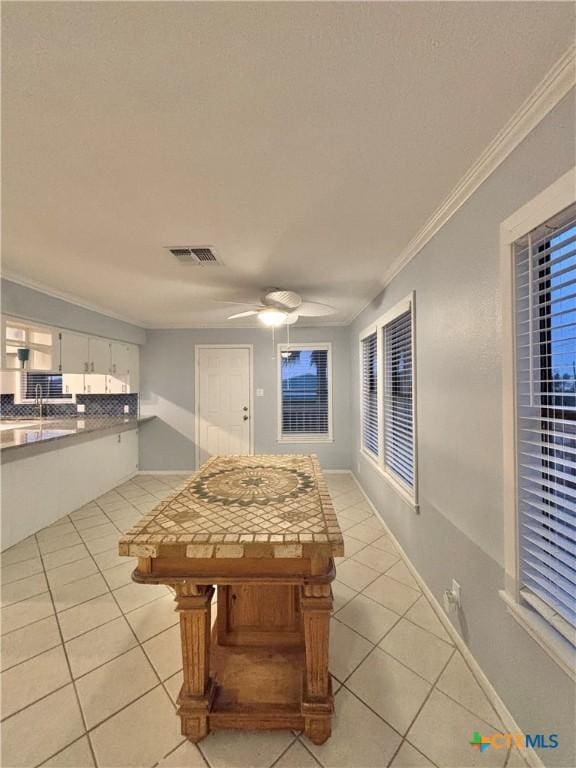 interior space featuring light tile patterned flooring, white cabinetry, tasteful backsplash, ornamental molding, and ceiling fan