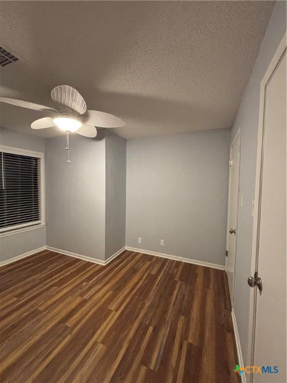 spare room featuring ceiling fan, dark wood-type flooring, and a textured ceiling