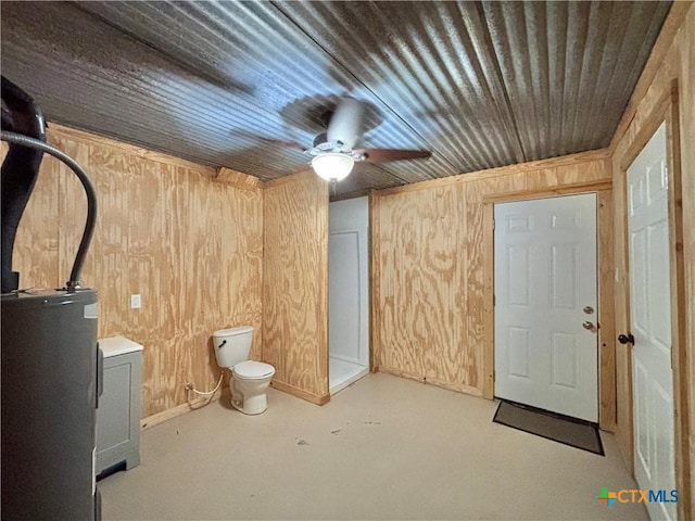 interior space with wood walls, water heater, concrete floors, toilet, and wooden ceiling