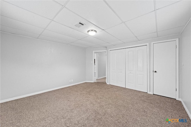 unfurnished bedroom featuring a closet, carpet, and a drop ceiling