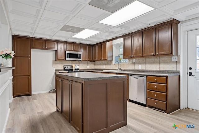 kitchen with tasteful backsplash, appliances with stainless steel finishes, sink, and a kitchen island