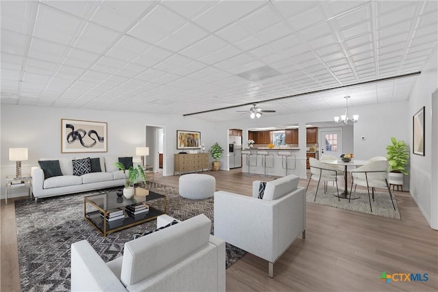 living room featuring hardwood / wood-style flooring and ceiling fan with notable chandelier