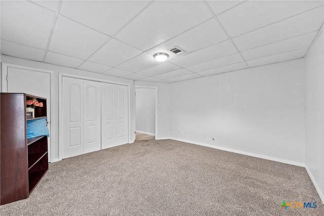 unfurnished bedroom featuring a drop ceiling, a closet, and carpet flooring