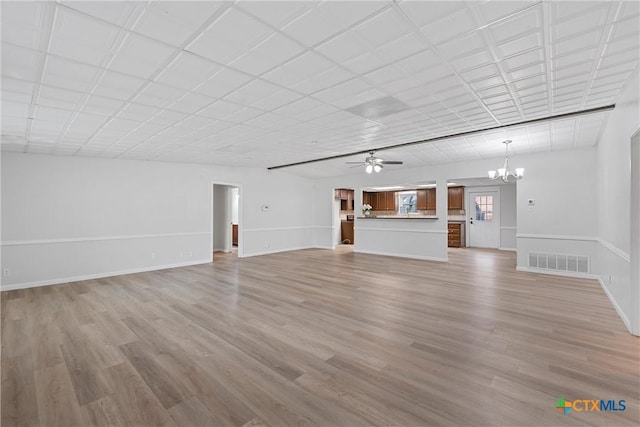 unfurnished living room featuring ceiling fan with notable chandelier and light hardwood / wood-style floors