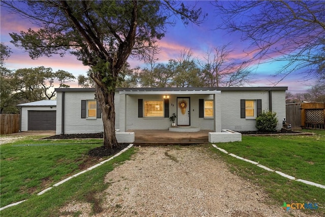 ranch-style house with a porch, a garage, and a yard