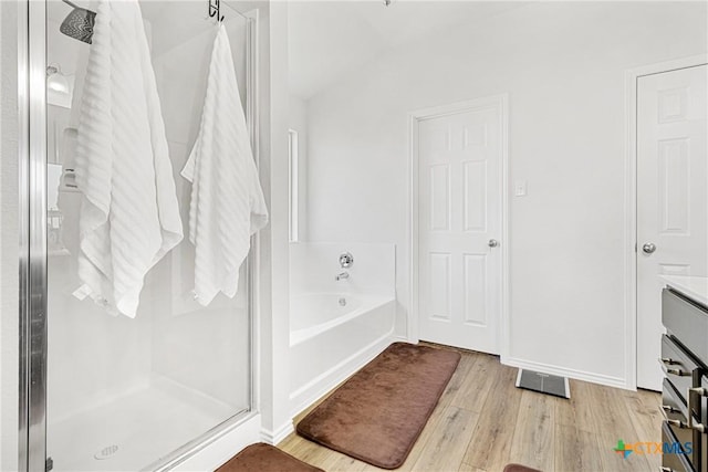 full bathroom with a bath, a stall shower, and wood finished floors