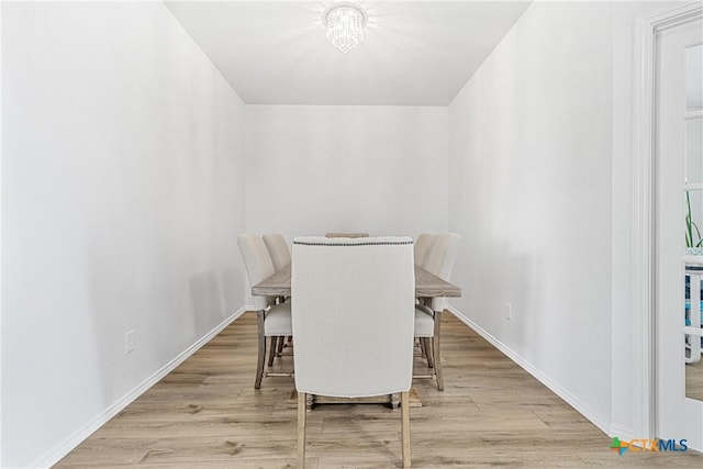 dining space with light wood-type flooring and baseboards