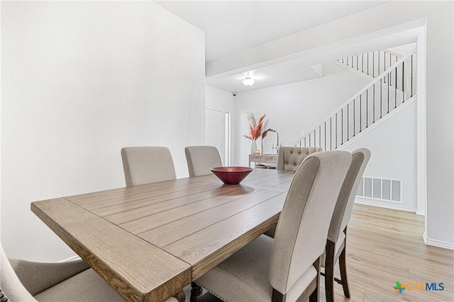 dining room with stairs, wood finished floors, visible vents, and baseboards