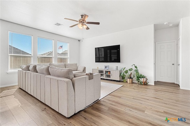 living room with a ceiling fan, visible vents, light wood-style flooring, and baseboards