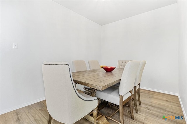 dining area with light wood-type flooring and baseboards