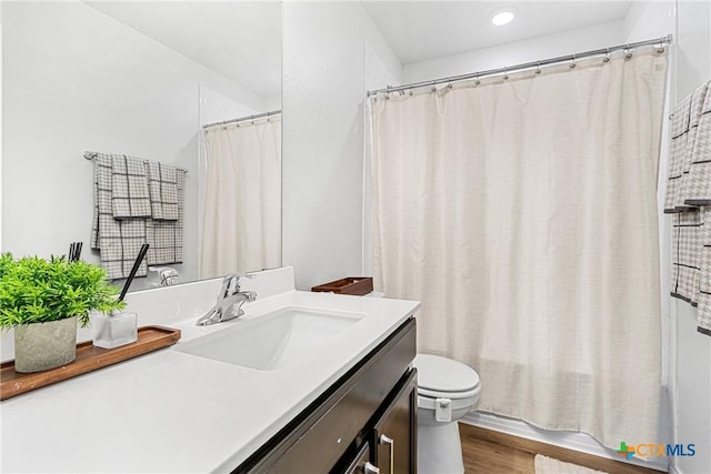 bathroom featuring vanity, toilet, and wood finished floors