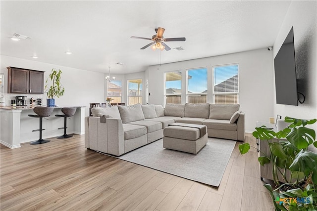 living area with light wood-style floors, baseboards, visible vents, and ceiling fan with notable chandelier