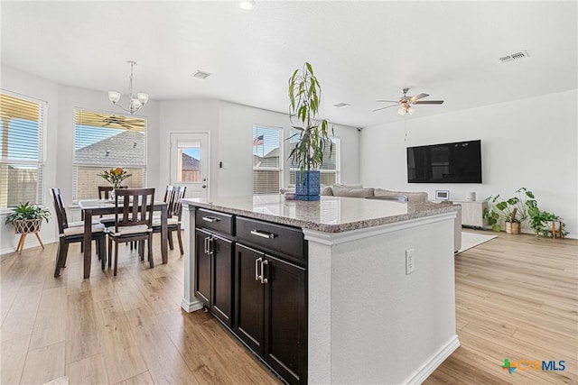 kitchen featuring light wood finished floors, a kitchen island, visible vents, and decorative light fixtures