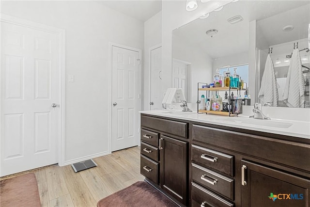 bathroom with double vanity, baseboards, a sink, and wood finished floors